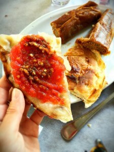 Malawach with customary grated tomato and chili topping. To the back, jachnun, a layered, caramelized bread baked overnight.