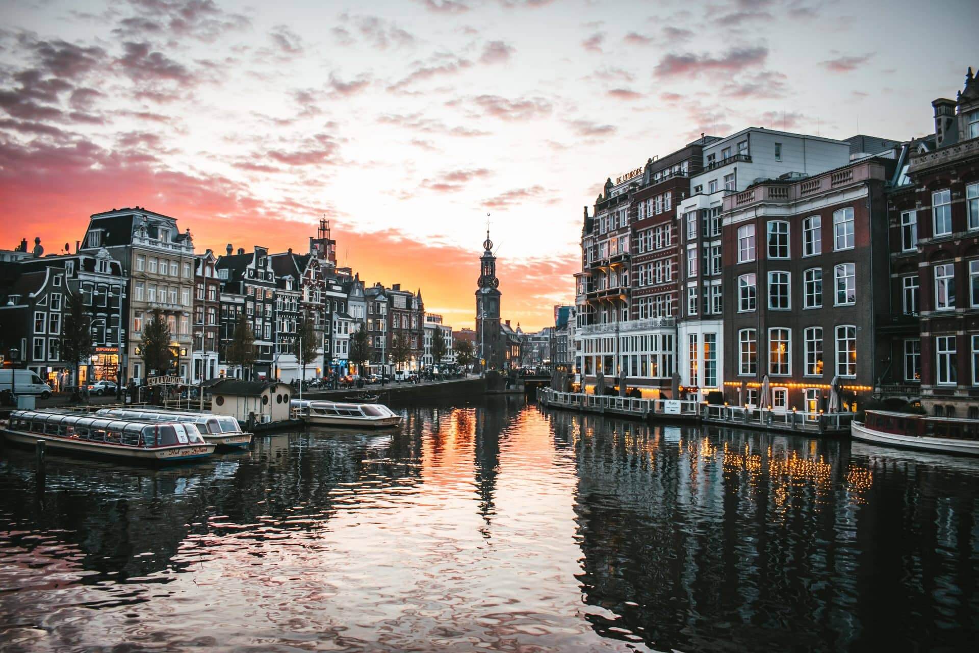 Amsterdam canal with buildings lining the water, hosueboats and ferrys