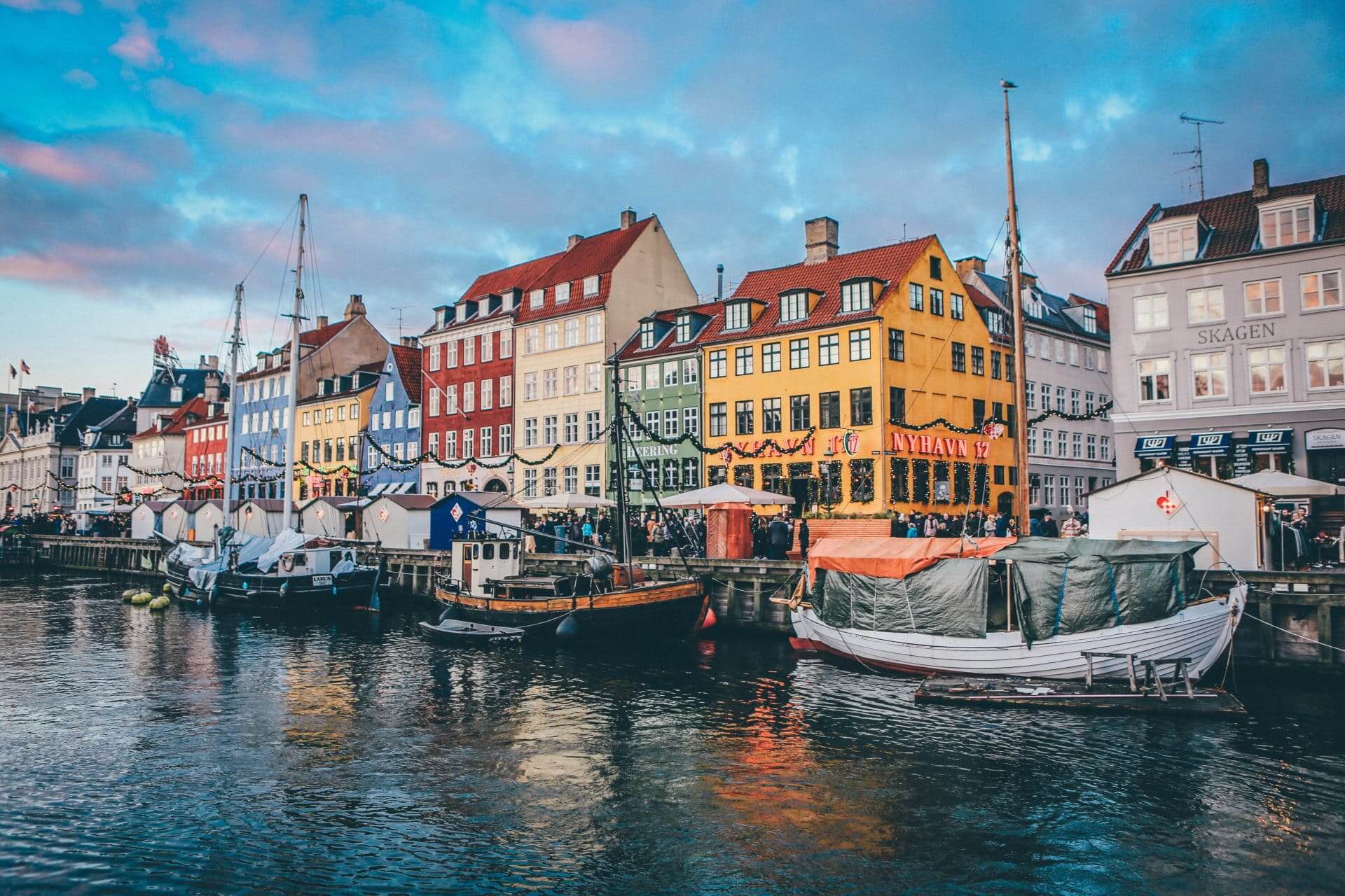 Copenhagen harbor on a Jewish heritage tour of Copenhagen. Boats in front of typical copenhagen buildings, one yellow, one green, one red.